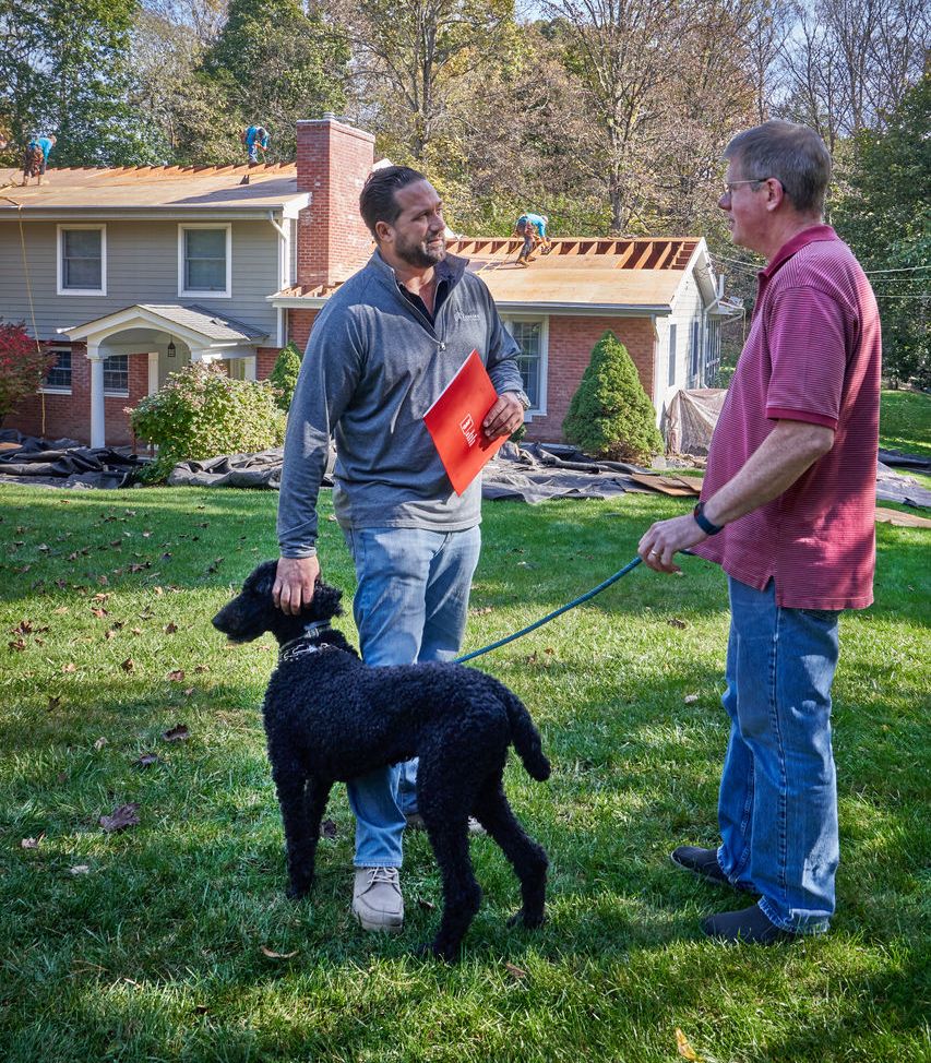 A professional roofer stops to talk to a neighbor about the roof damage on his home.