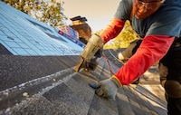 A roofer hitting the nail line on installation of Timberline HDZ Shingles