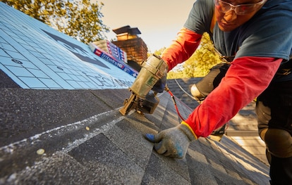 A roofer hitting the nail line on installation of Timberline HDZ Shingles