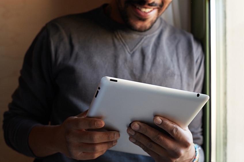 A man holding a tablet and smiling
