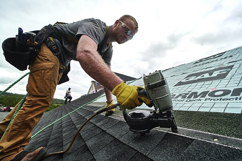 A man nailing shingles on a roof