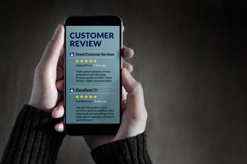 Two hands holding a phone with the words "Customer Review" on the screen