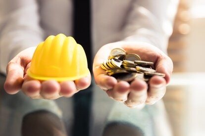 Outstretched hands holding a hard hat and coins