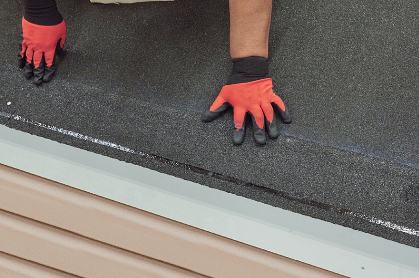 Contractor with red gloves installing a starter strip shingle
