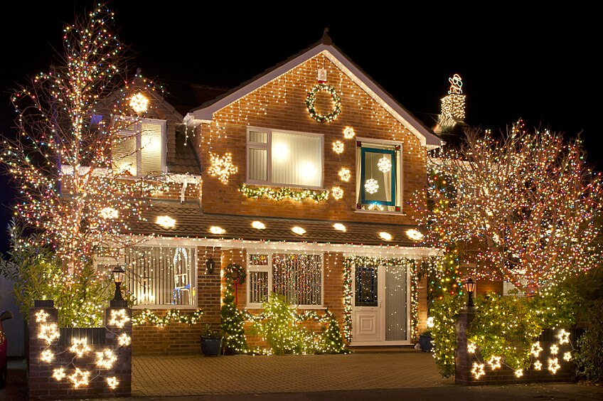A festive two-story house with holiday lawn decorations and holiday roofing decorations.