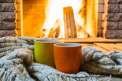 Two mugs in front of an actively lit fireplace