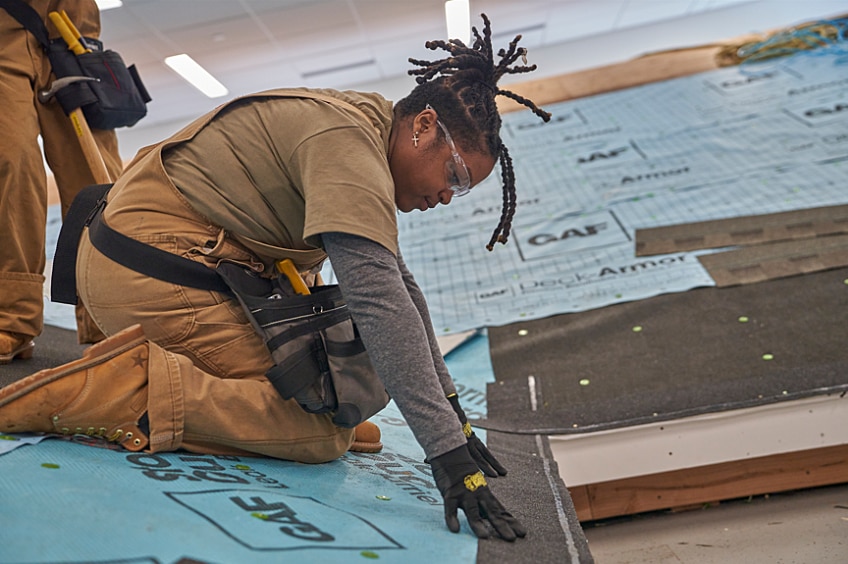 Woman construction worker focuses while using an industrial tool.