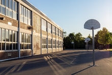 Schoolyard with basketball court and school building exterior in the sunny evening. School yard with