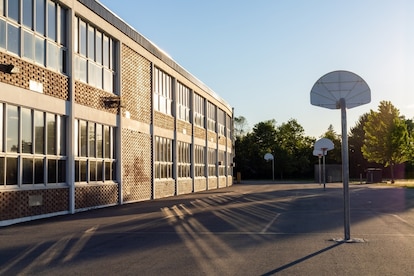Schoolyard with basketball court and school building exterior in the sunny evening. School yard with