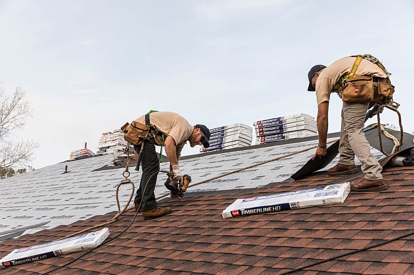 Two roofers installing GAF shingles.