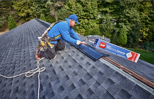 A roofer installs GAF's Cobra SnowCountry Advanced Premium Exhaust Vent on a Roof Ridge