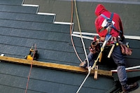 A metal roof system being installed on a home by a roofer.