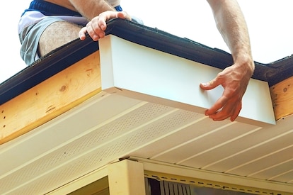 A roofing professional installs fascia on a home.