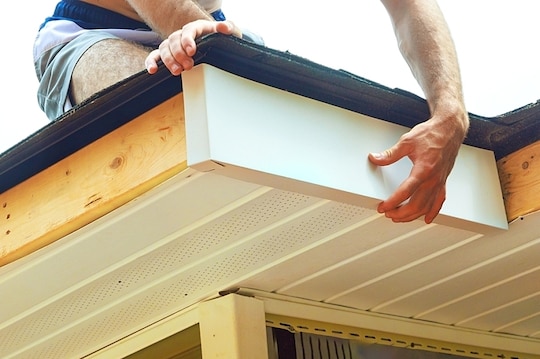 A roofing professional installs fascia on a home.