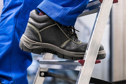 A person wearing roofing shoes while climbing a ladder.