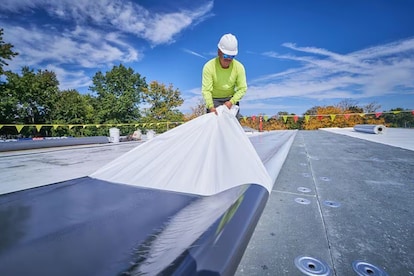 Roofer removing self-adhered TPO backing.