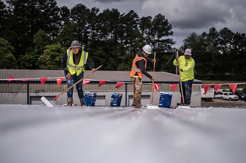 Roofers installing GAF Roof Coatings on a commercial roof