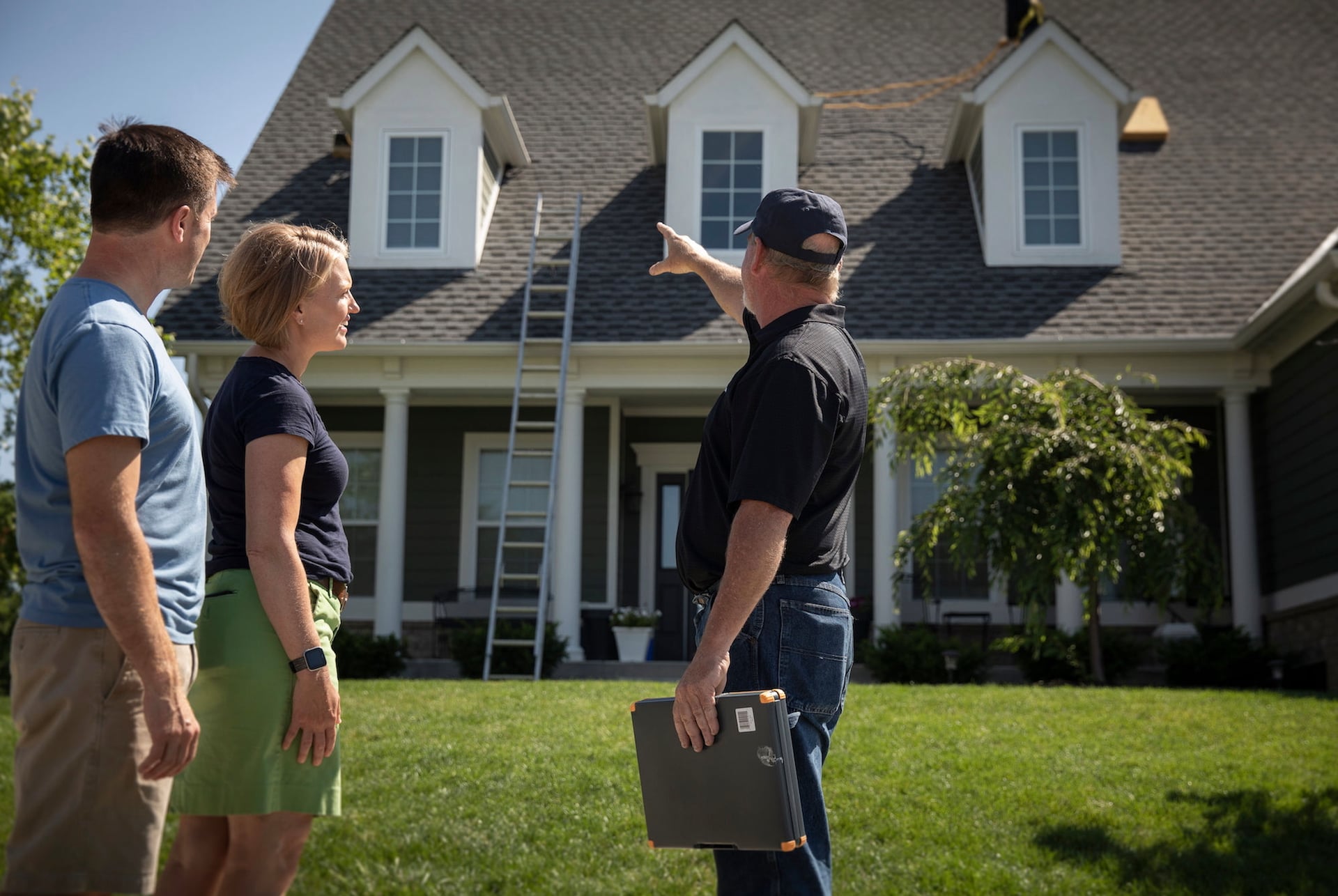 A roofer speaks with a couple outside their home