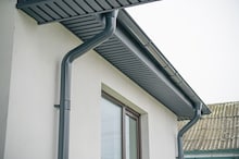 Close-up of a modern home featuring a gray gutter system and window, showcasing sleek architectural 