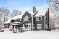 This snowy house with a large tree in the foreground is a striking image for a winter photo album
