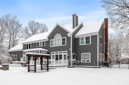 This snowy house with a large tree in the foreground is a striking image for a winter photo album