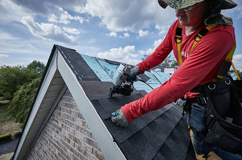 A roofer installs GAF Timberline AS II Shingles on a roof