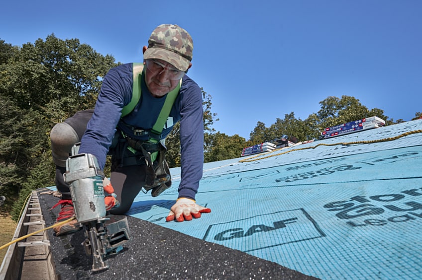 A roofer installing starter strip shingles before adding GAF roofing shingles