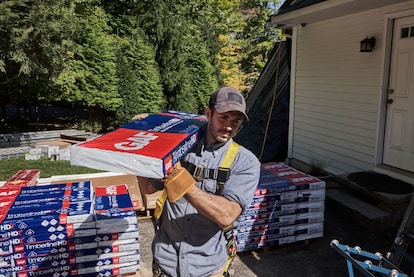 A roofer carries a bundle of GAF Timberline HDZ shingles.