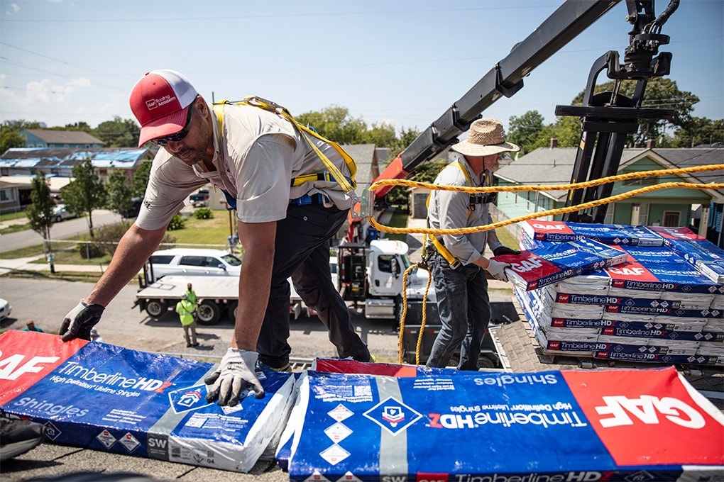 GAF Roofing Academy Instructor Gary Pierson grabs a pack of GAF roofing shingles while on a house.