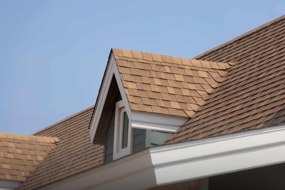 Brown roof shingles with sky in background.