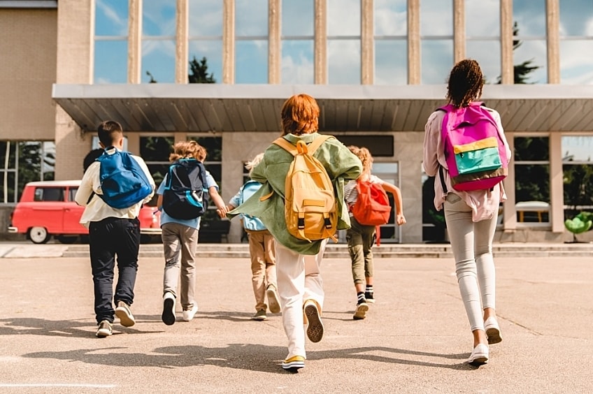 Children walking into school building for classes.