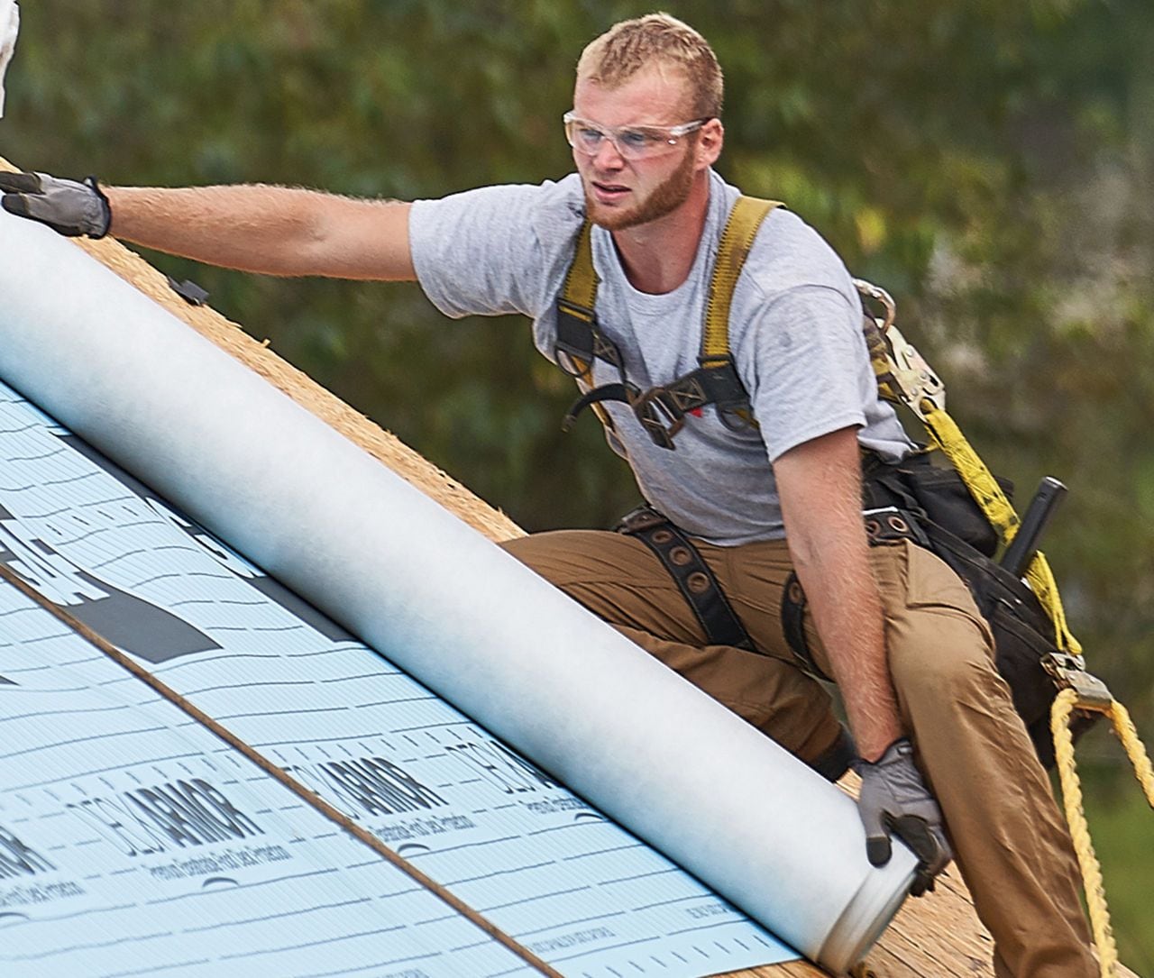 Professional roofer safely installs deck armor on the roof of a home