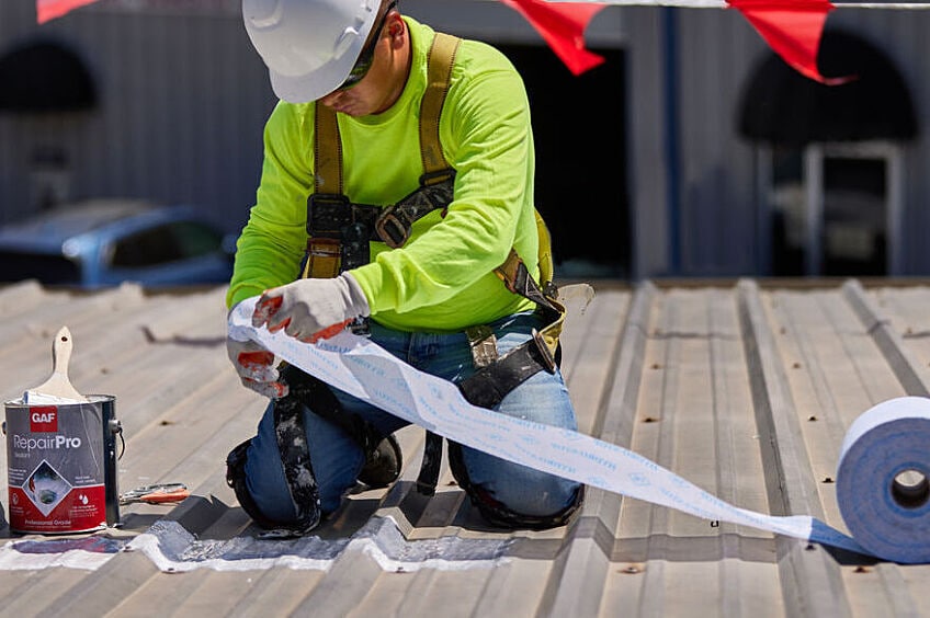 A professional roofer repairs a commercial roof using GAF products