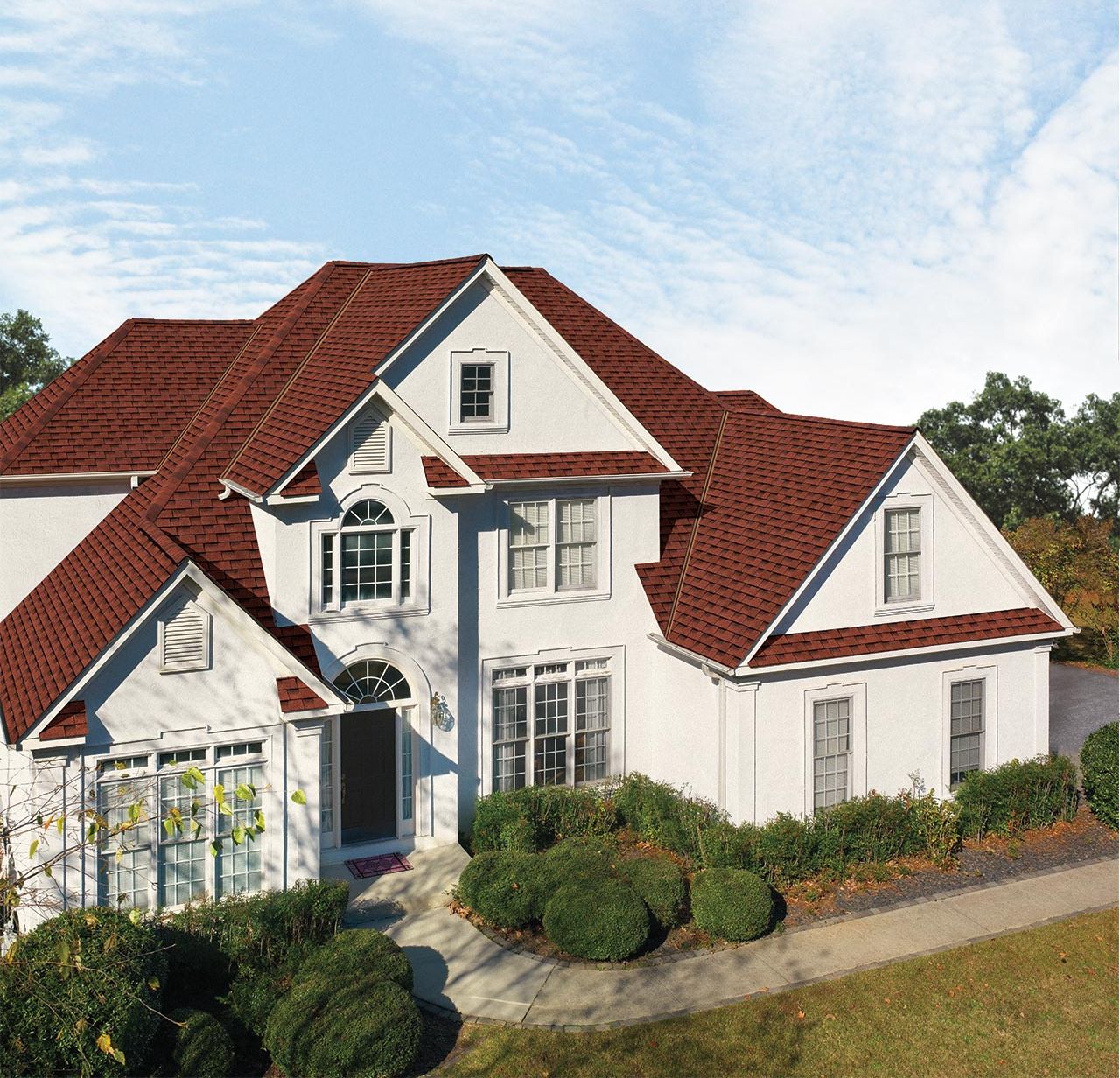 1c767e5e-86a3-47d6-9e4b-bcda05434705 Image of a white or cream color home with GAF's Timberline HDZ Patriot Red shingles installed on the roof.