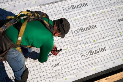 A roofer installs class a roofing fire rating underlayment; GAF FeltBuster.