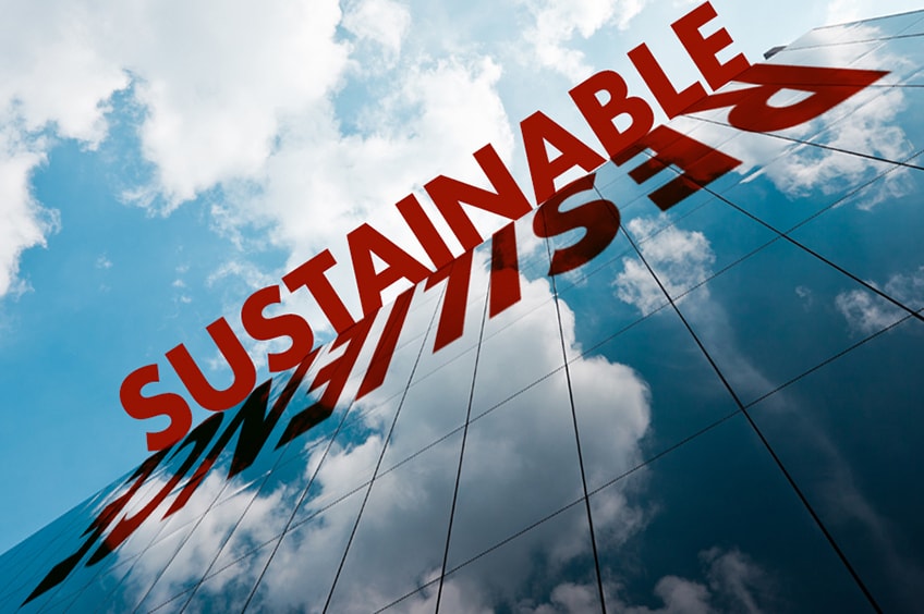 The words sustainable and resilience juxtaposed against a glass building.