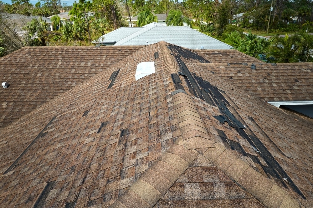 Damaged house roof with missing shingles after hurricane Ian in Florida. Consequences of natural dis