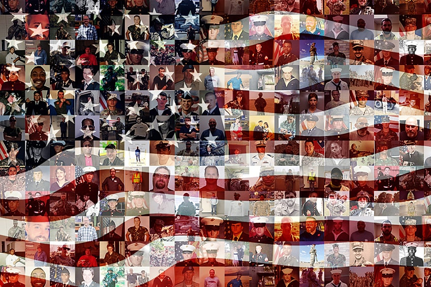 A group of manufacturer works smile and place hands together in a huddle wearing hard hats.