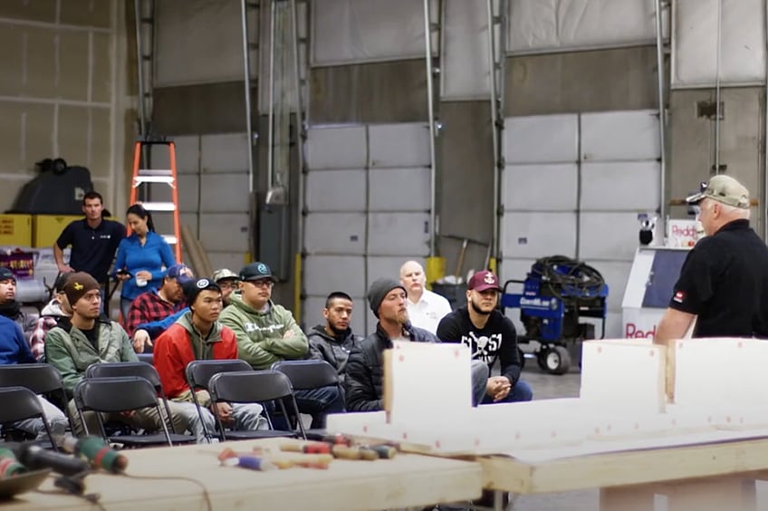 Roofing training instructor teaching students in a shop area.