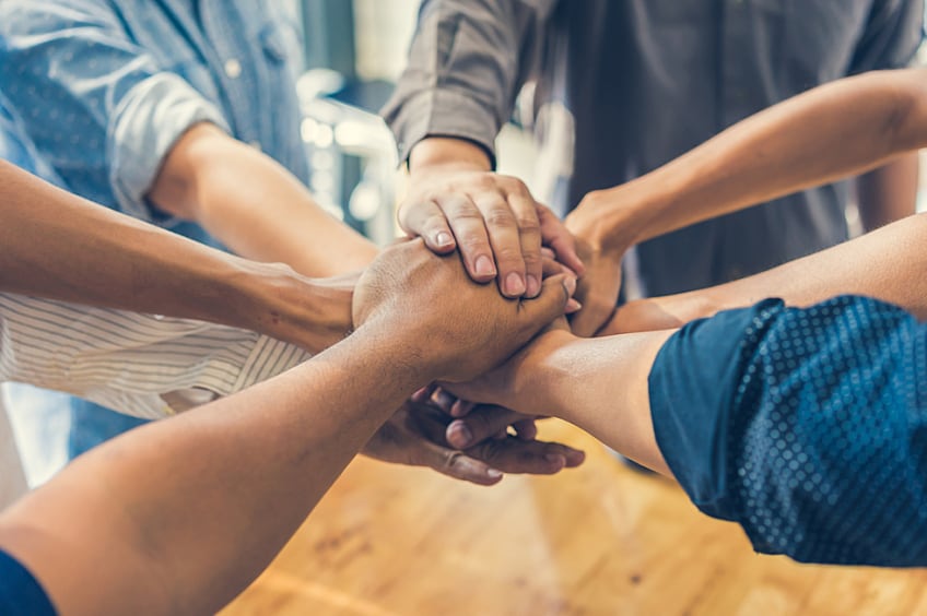 Two employees with disgruntled faces looking at each other while working on laptops